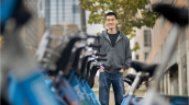 Xiaoxia Dong standing with hands in pockets next to rack of Indego rental bicycles in Philadelphia
