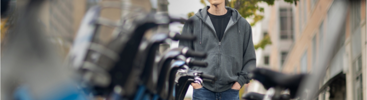 Xiaoxia Dong standing with hands in pockets next to rack of Indego rental bicycles in Philadelphia